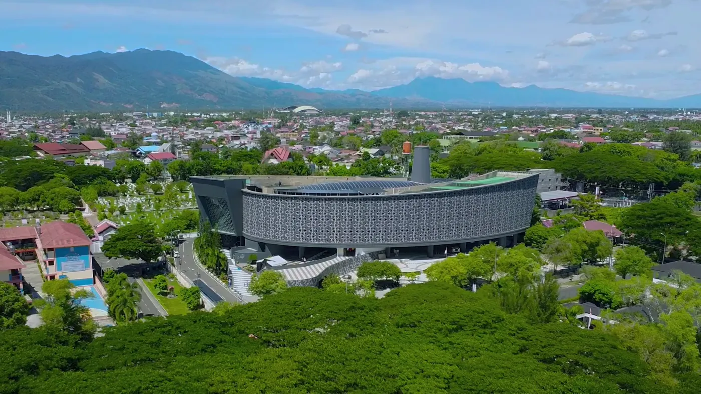 The Aceh Tsunami Museum, a long building with a patterned facade, among trees in Banda Aceh